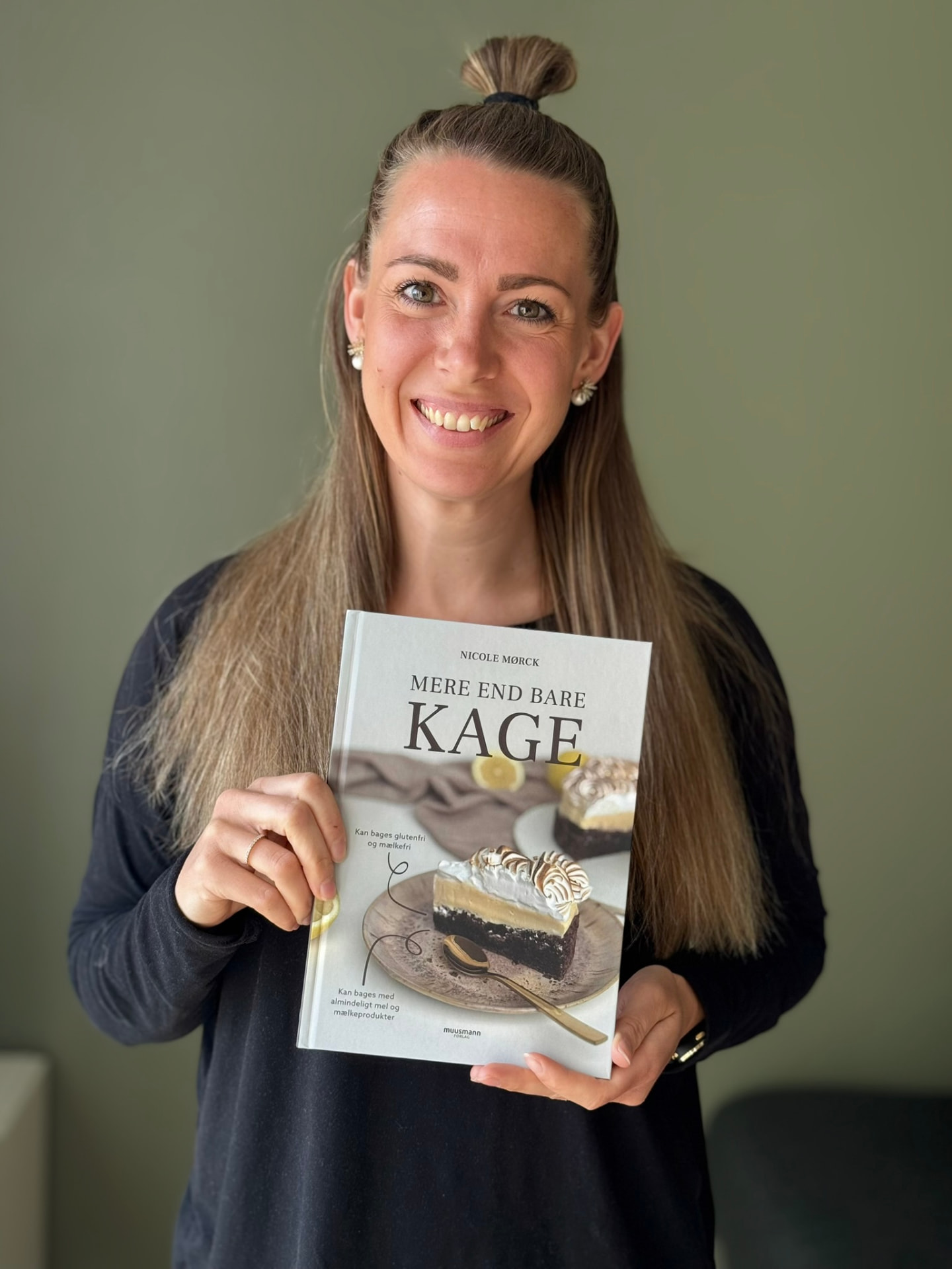 Nicole Mørck smiler og holder sin bog Mere end bare kage foran sig